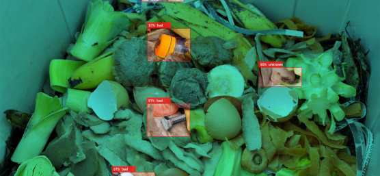 IDS 産業用カメラは、開いたゴミ収集容器に存在するプラスチックゴミを異物として認識し、有機廃棄物から区別します。