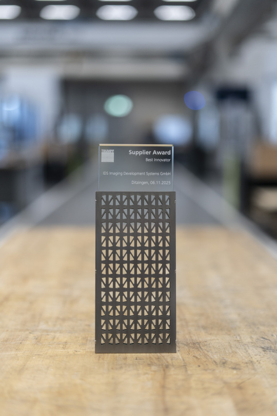 TRUMPFサプライヤーアワード「最優秀イノベーター賞」受賞：IDS Imaging Development Systems GmbH - 木製のテーブルに置かれたモダンな表彰盾、革新性を象徴