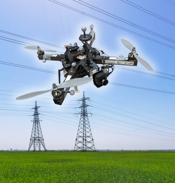 IDSカメラを搭載したドローンが、送電線と3本の送電塔の前をホバリングしている画像