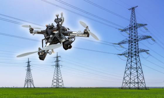 IDSカメラを搭載したドローンが、送電線と3本の送電塔の前をホバリングしている画像