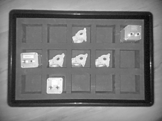 Nion 3Dカメラによるグレーの輝度画像は、仕分けトレイ付きの箱内の様々な物体を上面から捉えています。