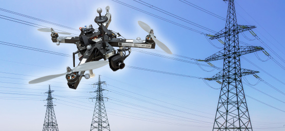 IDSカメラを搭載したドローンが、送電線と3本の送電塔の前をホバリングしている画像