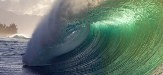 Eine große Welle in blau und grün überschlägt sich.