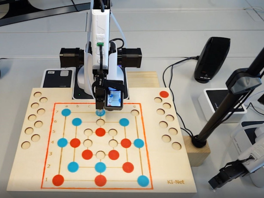 ミルゲーム盤の前に設置されたカメラ付きロボットアーム