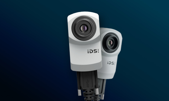 青い背景に設置された 2 台の IDS uEye XC 産業用カメラ。