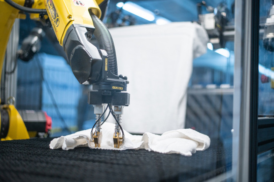 工業用ランドリーでタオルを広げる黄色いロボット。